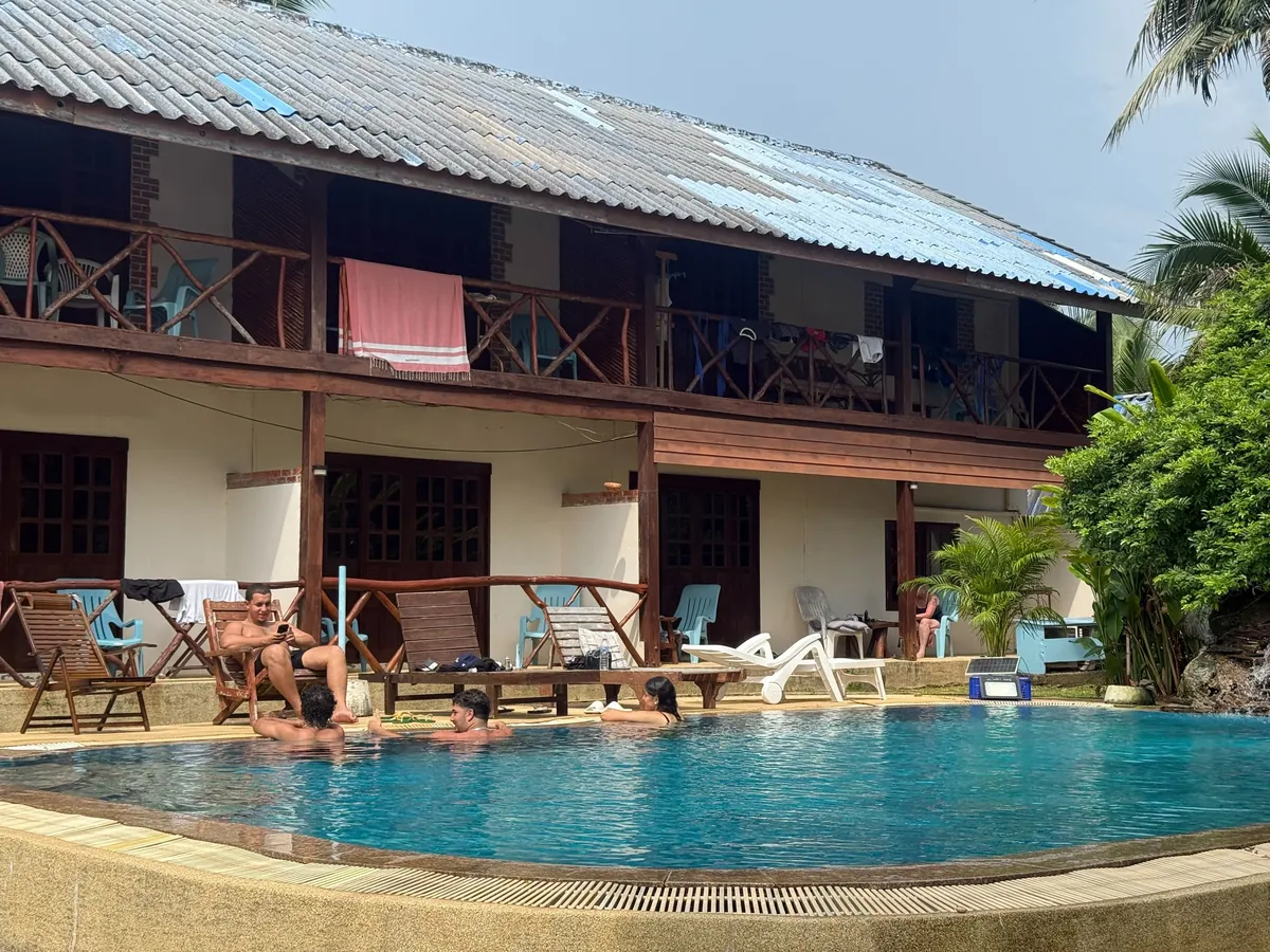 Guests relaxing around the pool in front of the rooms