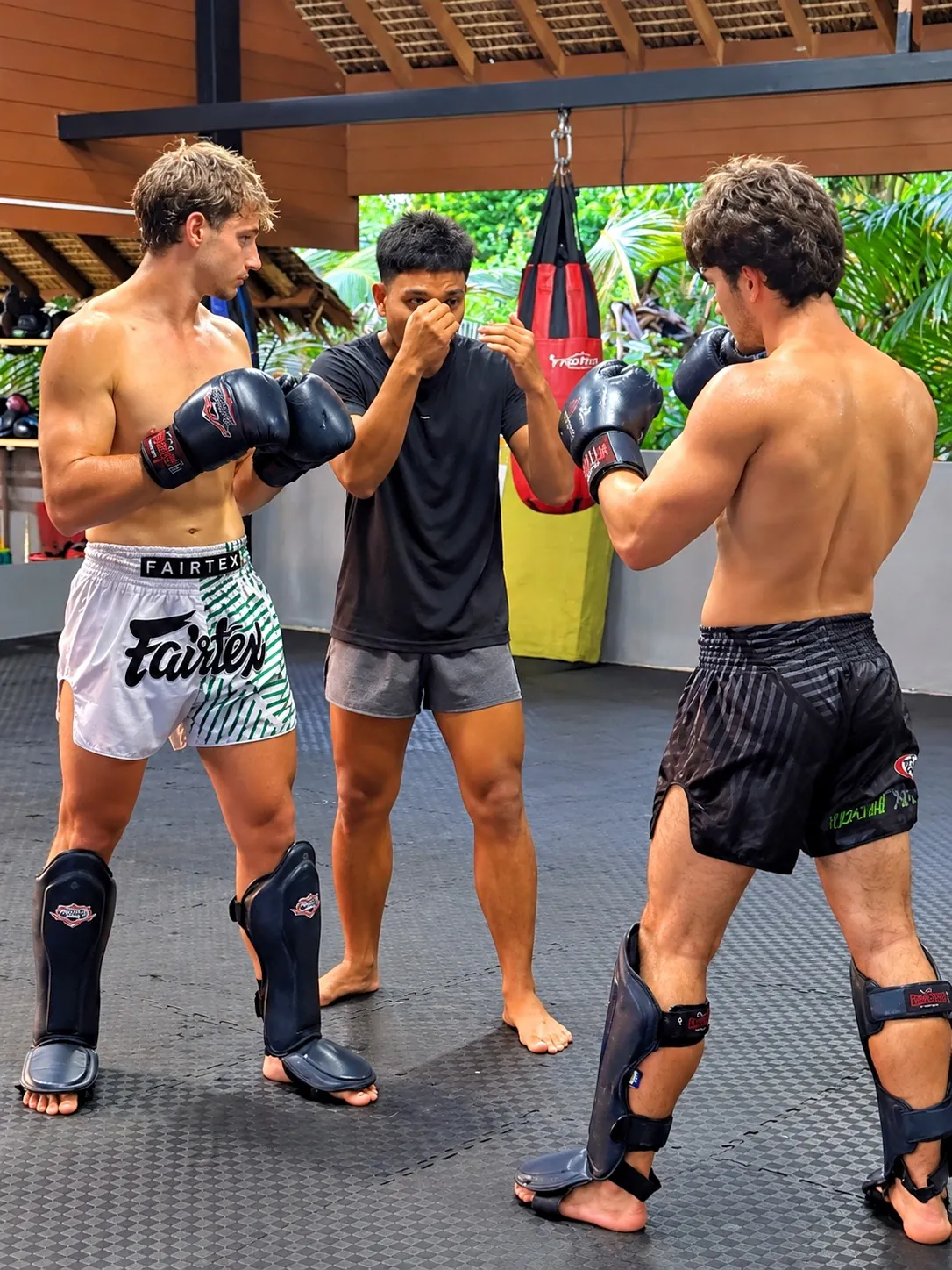 Muay Thai class: coach teaching two students