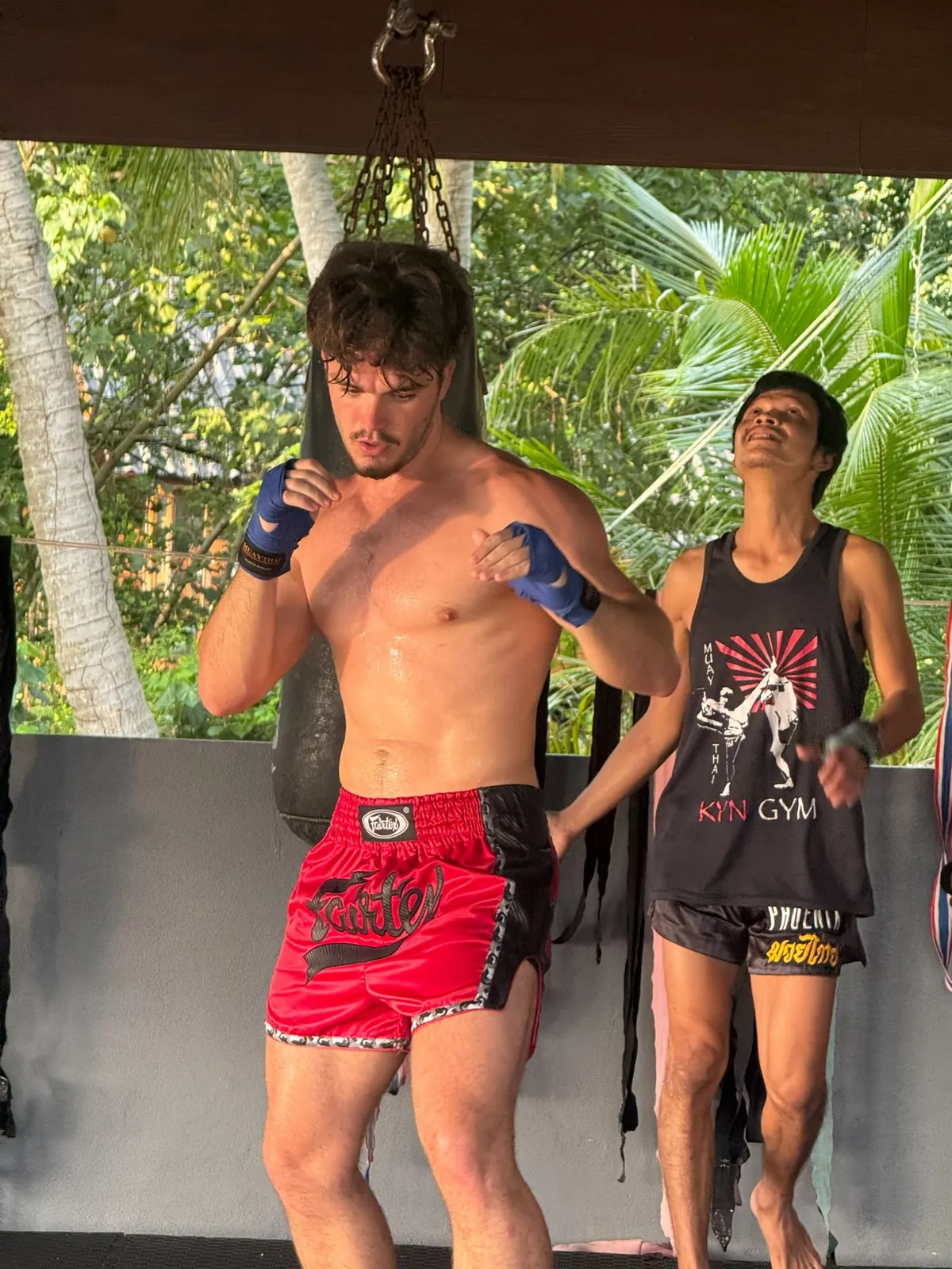Heavy bag work with a trainer in the open-air gym